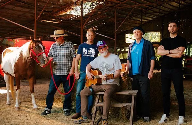 CAKE the band in a barn with a horse accompanying them