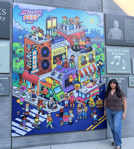 Kelly Sulca Hernandez standing next to the Musikfest 2027 Poster artwork on the ArtsQuest Center